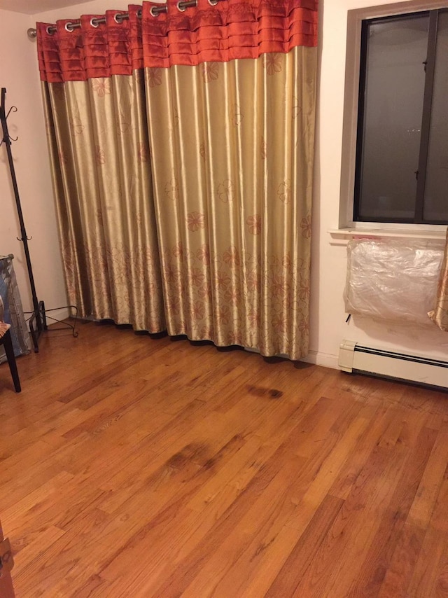 spare room featuring wood-type flooring and a baseboard radiator