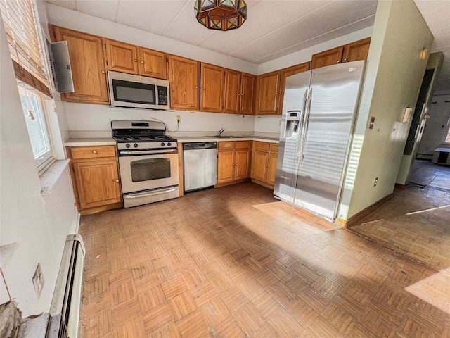 kitchen with light parquet floors, stainless steel appliances, a baseboard radiator, and sink