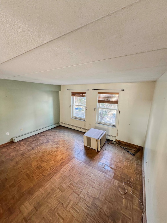 empty room featuring baseboard heating, parquet floors, and a textured ceiling