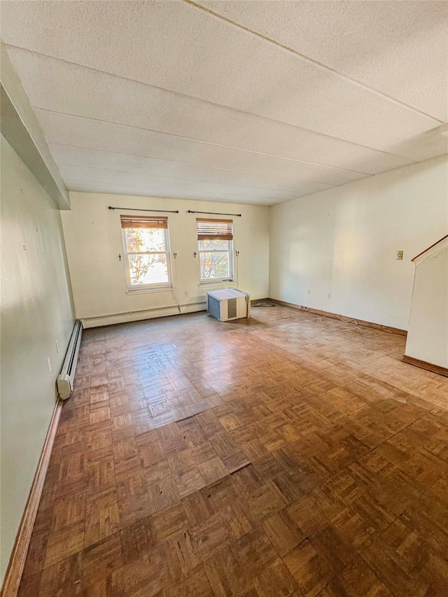 spare room with a textured ceiling, parquet flooring, and baseboard heating