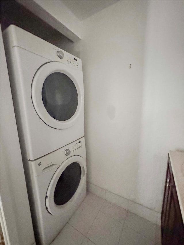 laundry room featuring light tile patterned floors and stacked washer / dryer