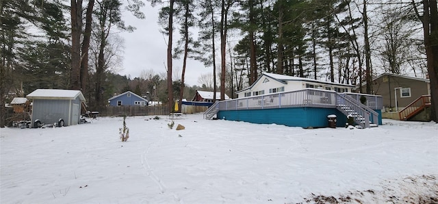 yard covered in snow with a deck and a storage shed