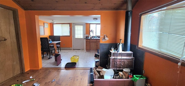 office featuring a baseboard heating unit, a wood stove, and wooden ceiling