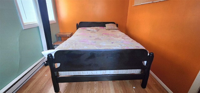 bedroom with hardwood / wood-style flooring and a baseboard radiator