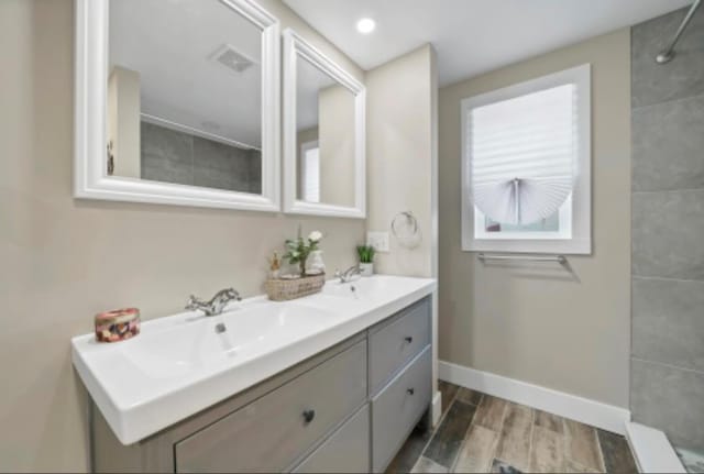 47 Prince St, Middletown, NY 10940 - bathroom with double vanity, baseboards, wood finish floors, and tiled shower
