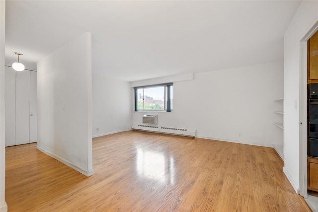 interior space with a baseboard heating unit, a wall mounted air conditioner, and light wood-type flooring