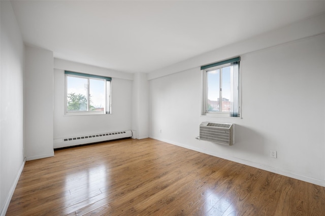 unfurnished room featuring wood-type flooring, a wall unit AC, and a baseboard radiator