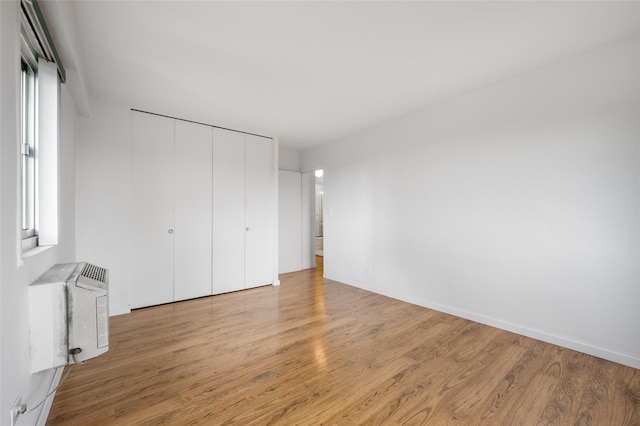 unfurnished bedroom featuring light hardwood / wood-style floors, a closet, and radiator heating unit