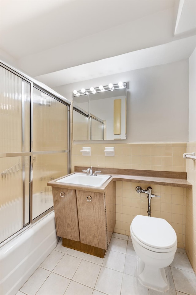 full bathroom featuring tile patterned floors, toilet, and tile walls