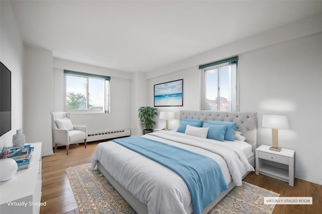 bedroom featuring a baseboard heating unit and wood-type flooring