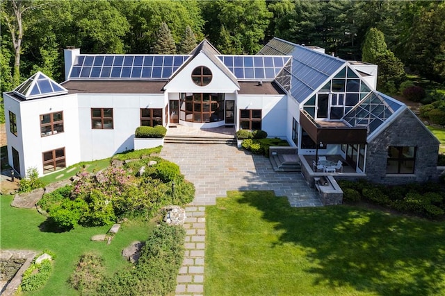 back of house featuring solar panels, a patio area, and a yard