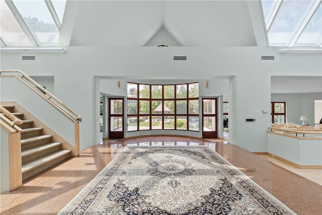 entryway featuring a skylight and high vaulted ceiling