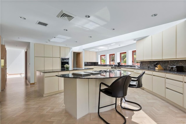 kitchen with a center island, kitchen peninsula, cream cabinets, oven, and light parquet flooring