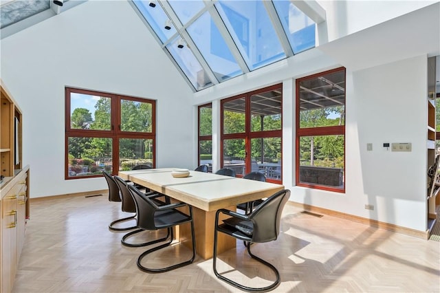 dining room featuring light parquet flooring, a healthy amount of sunlight, high vaulted ceiling, and a skylight