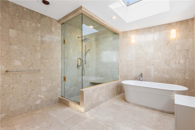 bathroom with a skylight, vanity, plus walk in shower, and tile walls