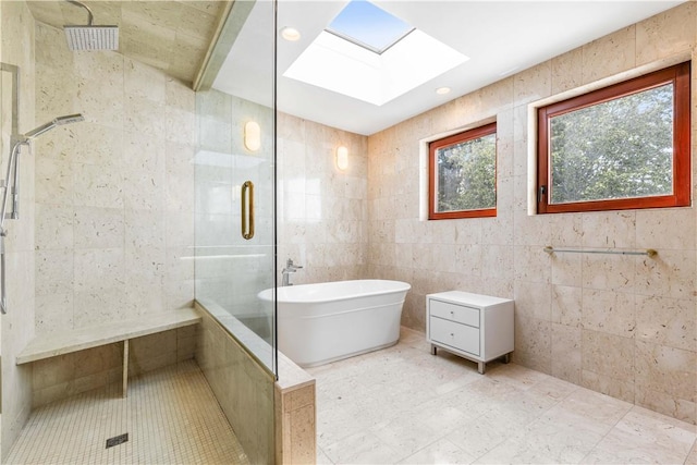 bathroom with a skylight, tile walls, and independent shower and bath