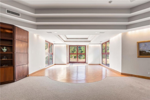 spare room featuring a raised ceiling and light parquet floors