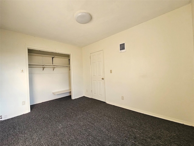 unfurnished bedroom with dark colored carpet and a closet