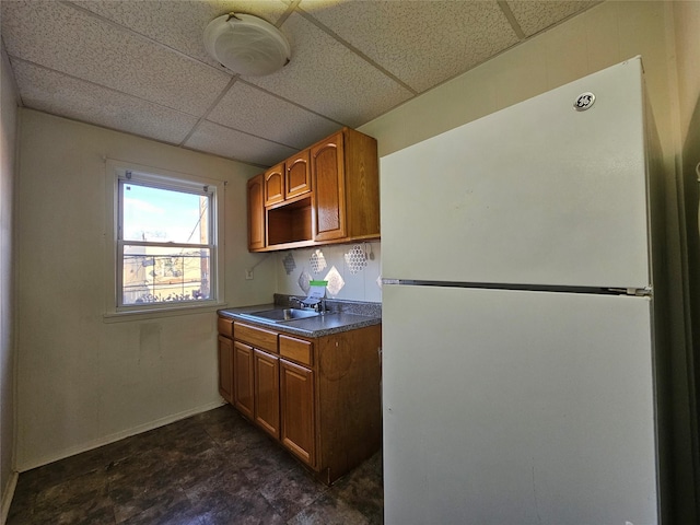 kitchen with a drop ceiling, white fridge, and sink