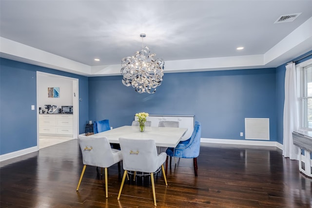 dining room with a notable chandelier, dark hardwood / wood-style flooring, and a tray ceiling