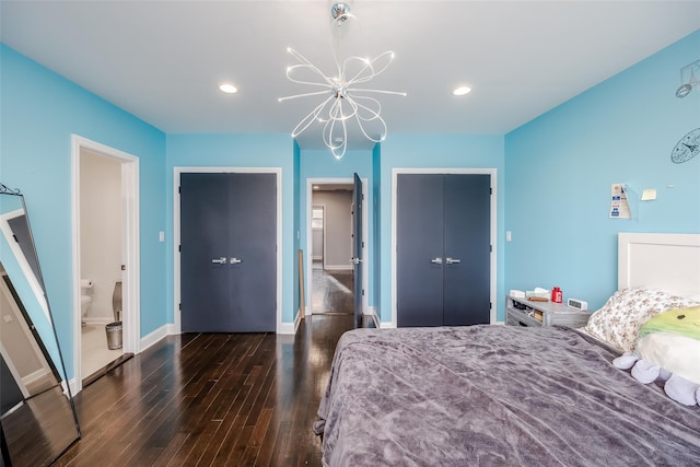 bedroom featuring ensuite bathroom, a closet, dark wood-type flooring, and an inviting chandelier