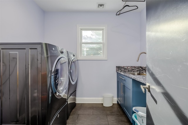 laundry area with cabinets, independent washer and dryer, dark tile patterned floors, and sink