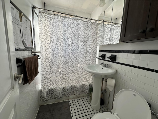 bathroom with tile patterned floors, toilet, tile walls, and shower / bath combo with shower curtain