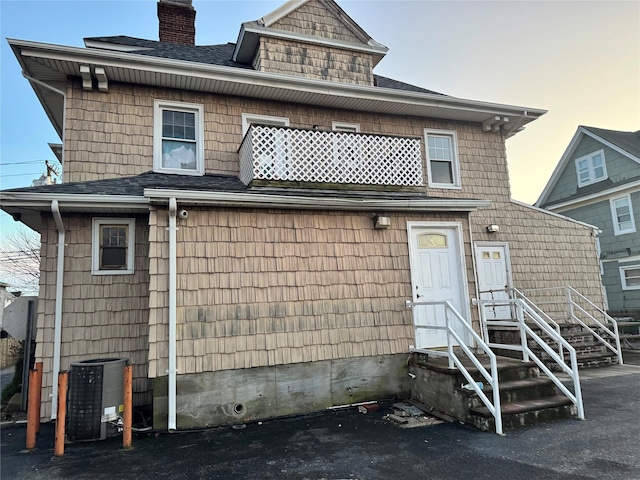 back house at dusk featuring cooling unit