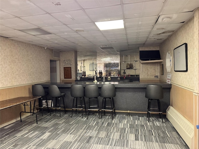 bar with a drop ceiling and a baseboard radiator