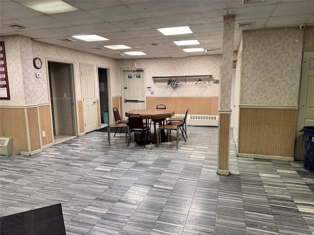 dining area with a drop ceiling and wood walls