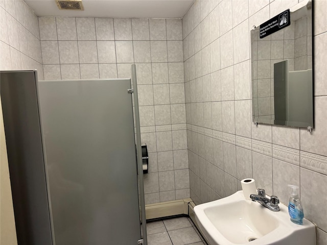 bathroom with tile patterned floors, sink, and tile walls