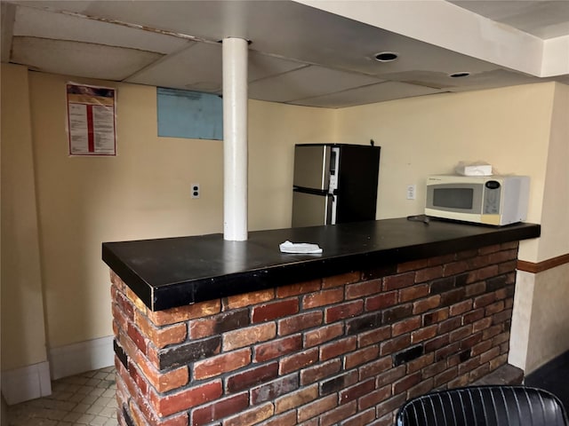 bar featuring tile patterned flooring and stainless steel fridge