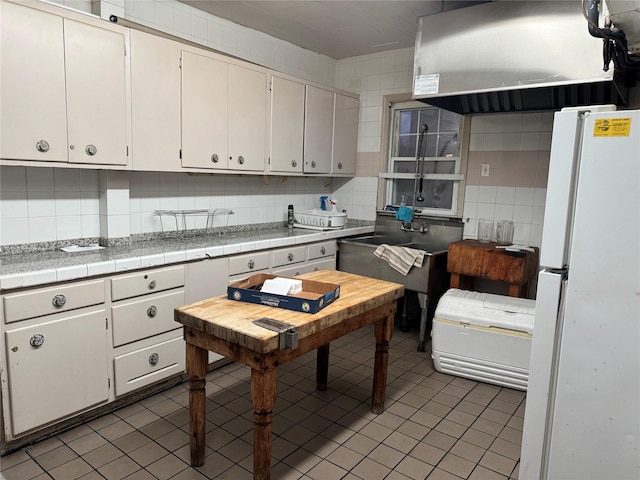 kitchen featuring tile counters, white refrigerator, and tasteful backsplash