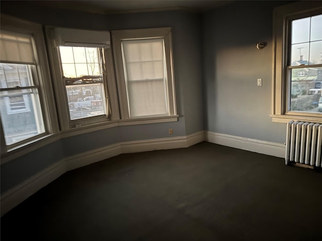 carpeted empty room featuring radiator heating unit