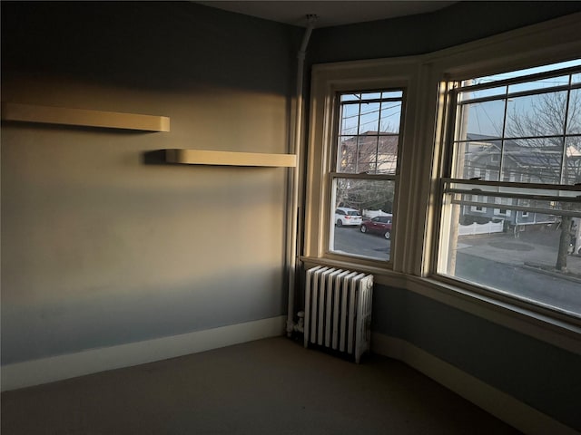 empty room with dark colored carpet and radiator