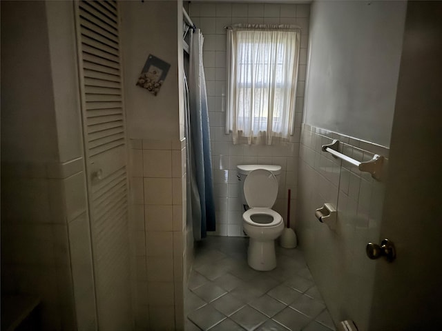 bathroom featuring tile patterned flooring, toilet, tile walls, and a shower with shower curtain