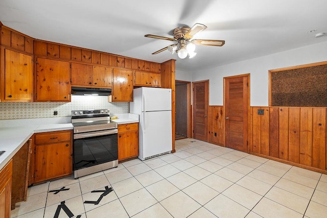 kitchen featuring tasteful backsplash, ceiling fan, electric range, white fridge, and wood walls