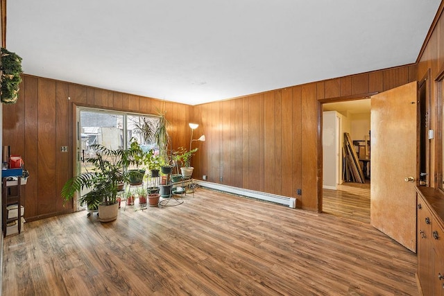 living area with wood walls, wood-type flooring, and a baseboard radiator