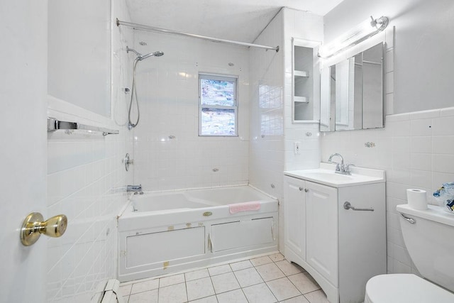 full bathroom featuring vanity, tile patterned floors, tiled shower / bath, toilet, and tile walls