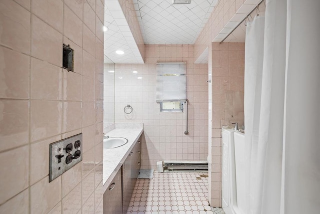 bathroom with tile patterned flooring, vanity, curtained shower, and tile walls