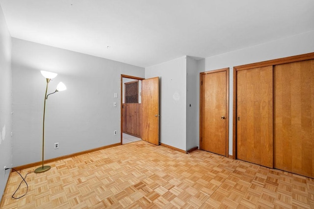 unfurnished bedroom featuring light parquet floors and two closets