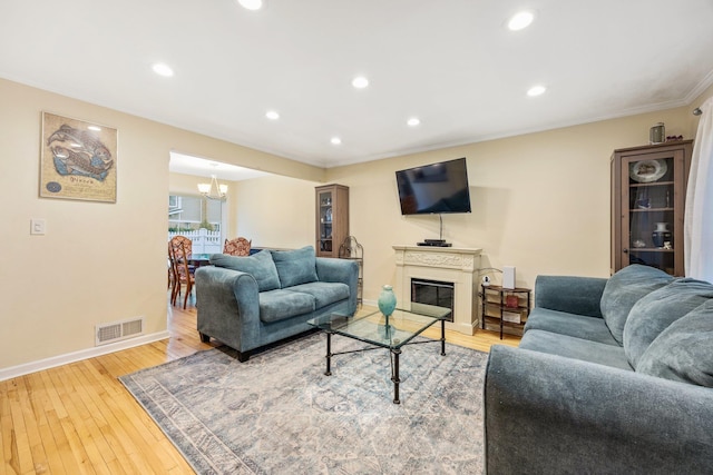 living room with a chandelier, wood-type flooring, and ornamental molding