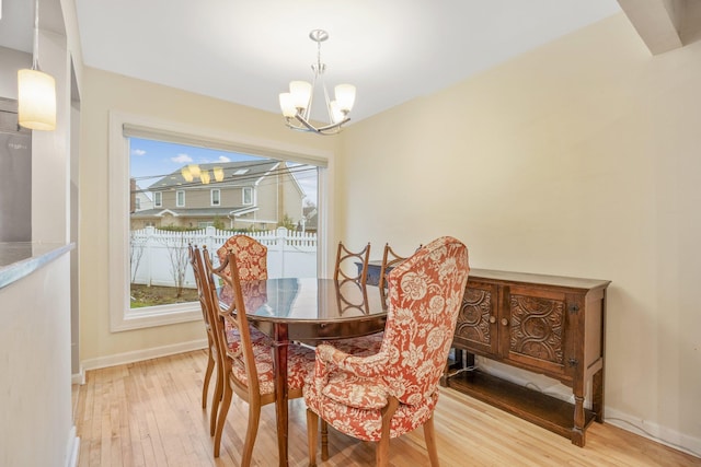 dining space featuring a wealth of natural light, light wood-type flooring, and a notable chandelier