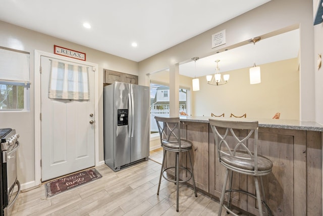 kitchen with a kitchen breakfast bar, plenty of natural light, pendant lighting, and appliances with stainless steel finishes