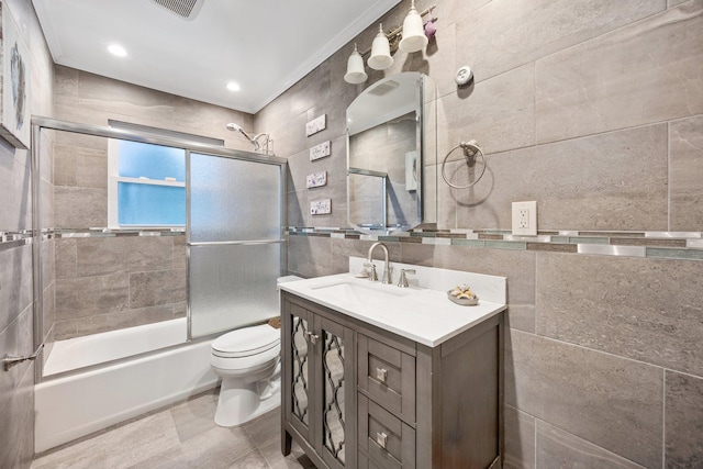 full bathroom featuring vanity, toilet, enclosed tub / shower combo, tile walls, and ornamental molding