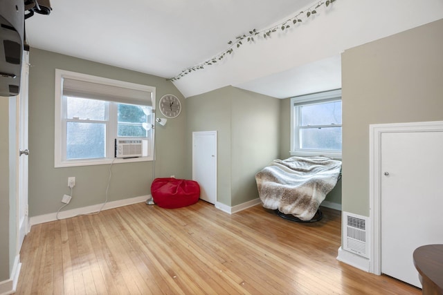 sitting room with light wood-type flooring, vaulted ceiling, plenty of natural light, and cooling unit