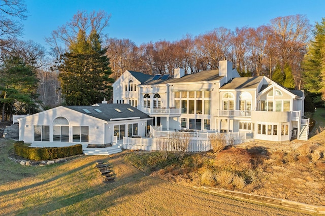 back of property with a yard and a balcony