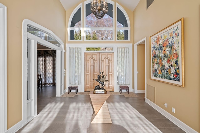 foyer with wood-type flooring, high vaulted ceiling, and an inviting chandelier