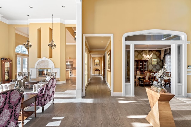 foyer entrance featuring wood-type flooring, a towering ceiling, an inviting chandelier, and ornamental molding