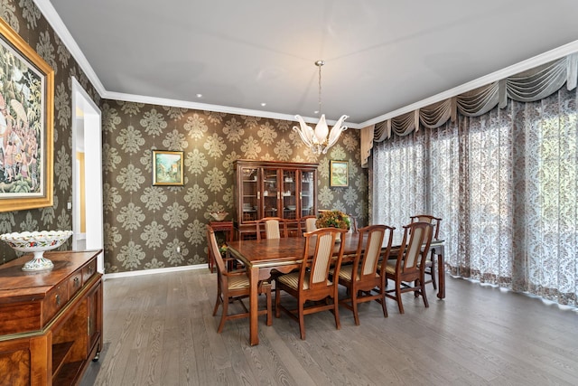 dining room featuring dark wood-type flooring, a wealth of natural light, ornamental molding, and a notable chandelier